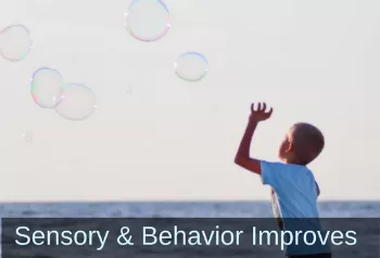 Photo of boy watching giant bubbles float above him. Text: Sensory & Behavior Improves.