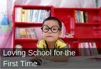 Boy with glasses in a library. Text: Loving school for the first time.