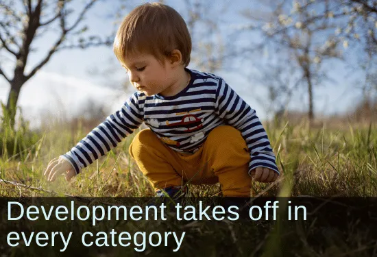Toddler boy picking up a stick outside in a feild. Text: Development takes off in every category.