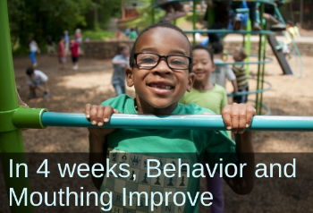 Smiling boy doing a pull-up on a playground. Text: In 4 weeks, Behavior and Mouthing Improve.