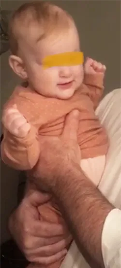 baby arching back with tight fists while being held by adult