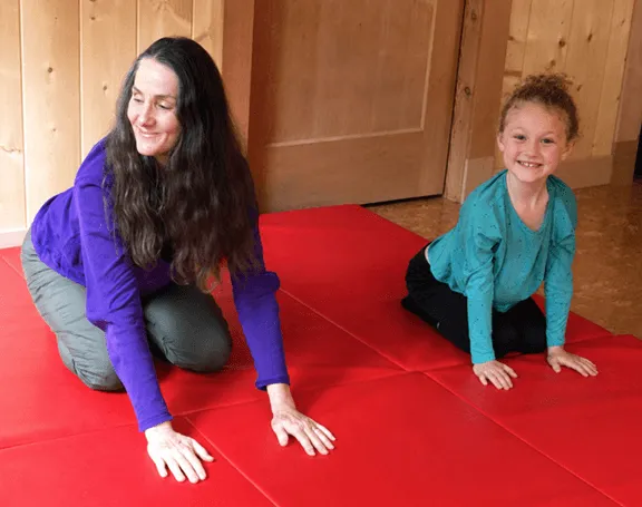 Image of Sonia Story, M.S. and a young girl doing neurodevelopmental movements on a red mat.