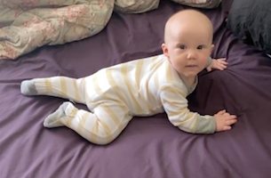 Baby in prone looking at camera, in belly crawl position