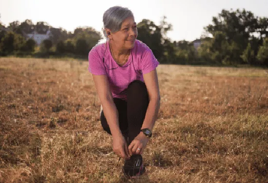Older woman on a walk, bending down to tie her shoes
