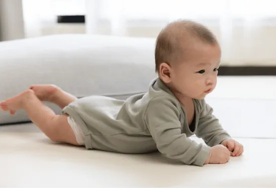 Baby laying on the floor in prone with head and chest raised, looking into the distance