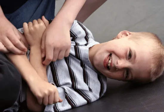 10-year-old boy on the ground being tickled.