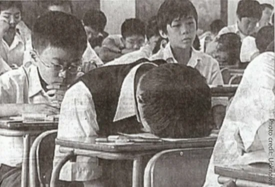 Black and white photo of boy slumped face-down on his desk. obviously exhausted.